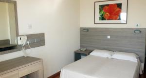 a small bedroom with a bed and a mirror at Marina Hotel in Ayia Napa
