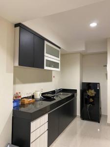 eine Küche mit schwarzer Arbeitsplatte und Kühlschrank in der Unterkunft MG Suites 1 Bedroom Apartment Sea View Semarang (KUMU SUITES) in Semarang