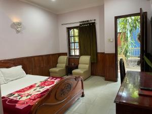 a bedroom with a bed and a desk and a window at Song Tra Hotel in Xóm Phước Mỹ