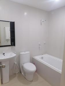 a white bathroom with a toilet and a bath tub at The Rose Garden House, Addu City, Maldives in Hithadhoo