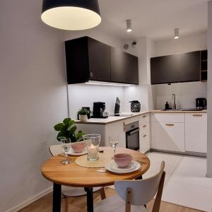 una pequeña cocina con mesa de madera y sillas en Apple Apartments - Wróblewskiego PRYWATNE MIEJSCE PARKINGOWE en Lodz