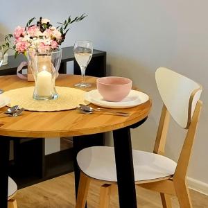 drewniany stół z miską i wazonem kwiatów w obiekcie Apple Apartments - Wróblewskiego PRYWATNE MIEJSCE PARKINGOWE w Łodzi