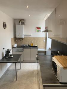 een keuken met witte kasten en een tafel. bij Appartement le Marilyn in La Tour-du-Pin