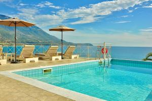 a swimming pool with chairs and umbrellas next to the ocean at Stone Villa Kefaloniaprivatevillas in Trapezaki
