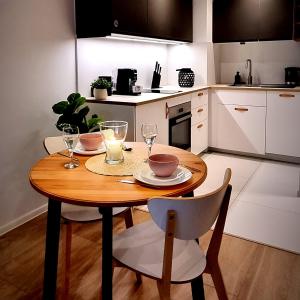 małą kuchnię z drewnianym stołem i krzesłami w obiekcie Apple Apartments - Wróblewskiego PRYWATNE MIEJSCE PARKINGOWE w Łodzi