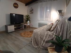 uma sala de estar com um sofá e uma televisão de ecrã plano em Gîte L'Ecureuil*** em MouscardÃ¨s