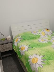 Una cama con una manta verde con flores blancas. en Andri' s place en Nea Paphos