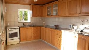 a kitchen with wooden cabinets and white appliances at Antigoni's Cottage in Choulou