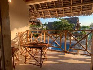 a porch with a table and chairs on a balcony at ZANZIBAR TROPICAL SUNSET - Adults Only Boutique Hotel by Sofia Collection in Kiwengwa