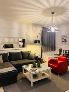 uma sala de estar com um sofá e uma cadeira vermelha em Gianna’s apartment central Aigio Cozy and Shining em Aigio