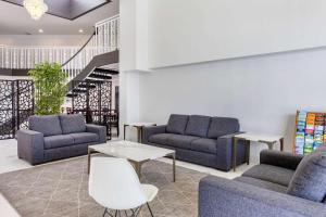 a lobby with couches and tables and a staircase at The Buena Park Hotel & Suites in Buena Park