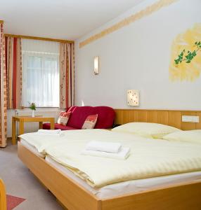 a bedroom with a large bed and a red couch at Stadthotel Raabs an der Thaya in Raabs an der Thaya