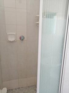 um chuveiro com uma porta de vidro ao lado de um WC em Villa Monique Self Catering Apartment em Sedgefield