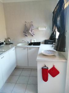una cocina con armarios blancos y una cesta roja en la encimera en Villa Monique Self Catering Apartment, en Sedgefield