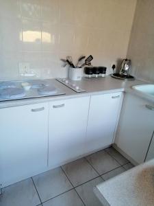 a white kitchen with white cabinets and a sink at Villa Monique Self Catering Apartment in Sedgefield
