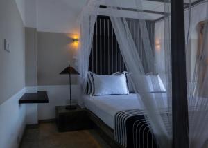 a bedroom with a canopy bed with white pillows at Temptation in Hikkaduwa