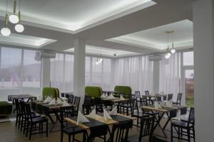 a dining room with tables and chairs and windows at Green Garden Resort in Cicîrlău