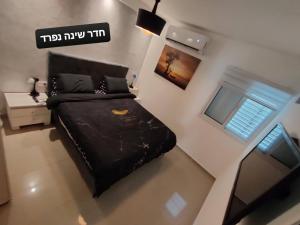 Un pequeño dormitorio con una cama negra y una ventana en דירות נופש וג'קוזי באילת - אילן vip en Eilat