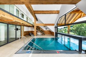 an indoor swimming pool in a house with windows at SCHWARZENBACH - Apartments & Rooftop Pool in Feldberg