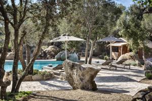 a pool with two umbrellas and chairs and a swimming pool at Gallicantu Stazzo Retreat in Luogosanto