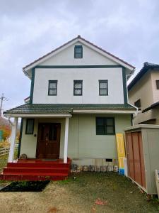 a white house with a red front porch at Shanshui House 箱館山 in Imazu