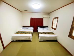 two beds in a room with a red curtain at Shanshui House 箱館山 in Imazu