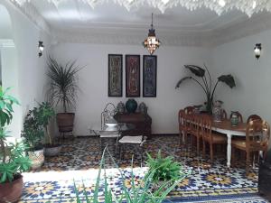 uma sala de estar com mesa, cadeiras e plantas em Riad Vega em Fez