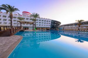 ein Hotelpool mit einem Kreuzfahrtschiff im Hintergrund in der Unterkunft Transatlantik Hotel & Spa in Kemer