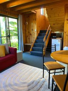 a living room with a red couch and a staircase at The Wombat Cottage in Tullah