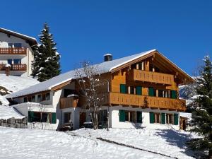 ein großes Holzgebäude mit Schnee auf dem Boden in der Unterkunft Landhaus Alpenland in Zug