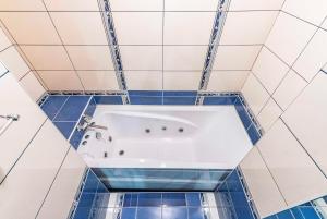 a bath tub in a bathroom with blue tiles at Гостиница Большой Урал in Yekaterinburg