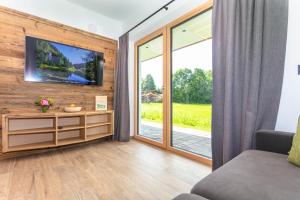 ein Wohnzimmer mit einem TV und Glasschiebetüren in der Unterkunft Biobauernhof Mittermoos in Fieberbrunn