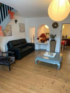 a living room with a black couch and a table at SUPERBE TRIPLEX MEUBLÉ TOUT CONFORT HYPER CENTRE ST CÉRÉ 3 CHAMBRES WIFI 120 M2 8 pers max in Saint-Céré