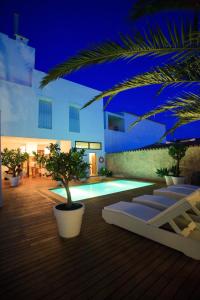 a building with a pool with a palm tree in it at Hotel Es Marès in Sant Francesc Xavier