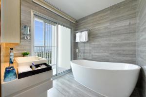a white bath tub sitting next to a large window at Centre Point Prime Hotel Pattaya in Pattaya North