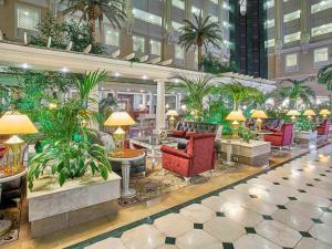 a lobby with chairs and plants in a building at Rixos President Hotel Astana in Astana