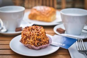 un pezzo di torta su un piatto con due tazze di caffè di SET Hotel.Residence by Teufelhof Basel a Basilea