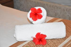 a towel with two red flowers on a bed at Reef Holiday Apartments in Anse aux Pins +38 photos