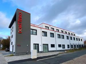 un grande edificio bianco con un cartello rosso di DORMERO Hotel Darmstadt a Darmstadt