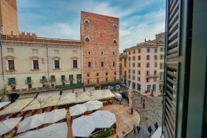 uitzicht op een straat met parasols en gebouwen bij ApartmentsArena - Suite Mercatorum - Piazza Erbe in Verona