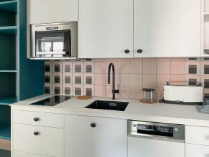 kuchnia z białymi szafkami i zlewem w obiekcie Appartements Steiner - SKI IN - SKI OUT w mieście Zell am See