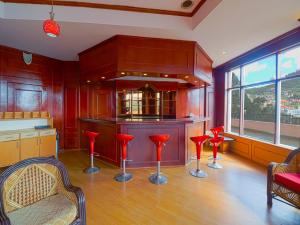 a kitchen with red bar stools and a counter at The Byke Sunshine Grand in Ooty