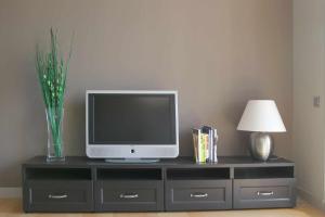a tv on a black dresser with a lamp and a vase at Passeig de gracia sun apartament balcony 2 bedroo in Barcelona