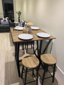 einen Holztisch mit Stühlen, Tellern und Weingläsern in der Unterkunft Gladstone Apartments by Bluebell Rooms in Southampton