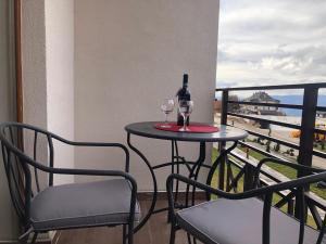 uma mesa com 2 copos e uma garrafa de vinho na varanda em Snaer Milmari Apartman Kopaonik em Kopaonik