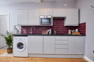 uma cozinha com armários brancos e uma máquina de lavar e secar roupa em Delven House, Apartment 3 em Castle Donington
