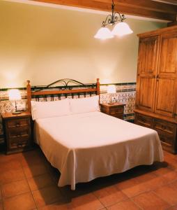 a bedroom with a large white bed and two night stands at Apartamentos Los Rosales de Isabel in Corral de Ayllón