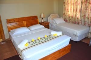 Dos camas en una habitación de hotel con flores. en Reef Holiday Apartments en Anse aux Pins