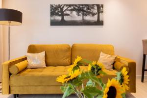 ein Wohnzimmer mit einer gelben Couch mit Sonnenblumen in der Unterkunft Platinum Towers E-Apartments in Warschau