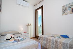 due letti in una stanza bianca con una finestra di APARTMENT BLANCO - Regarda Travel a Lazise